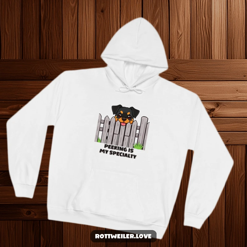 Funny Rottweiler Hoodie: A Rottweiler with a cheeky grin peeks out from behind a fence, ready to protect.