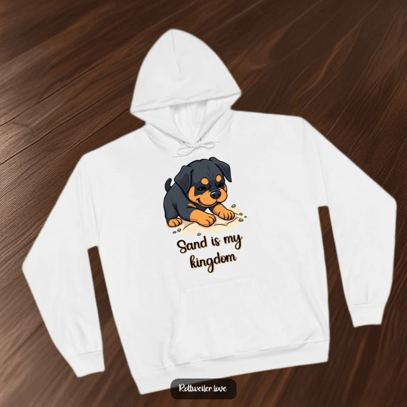 Funny Rottweiler hoodie depicting a dog playfully digging in soft sand, offering cozy comfort and lighthearted humor.