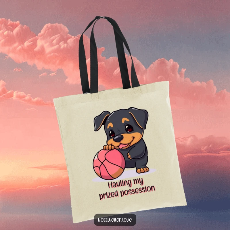 Funny Rottweiler tote bag featuring a dog playfully nudging a large, bouncy ball, perfect for everyday use with a dose of canine fun.